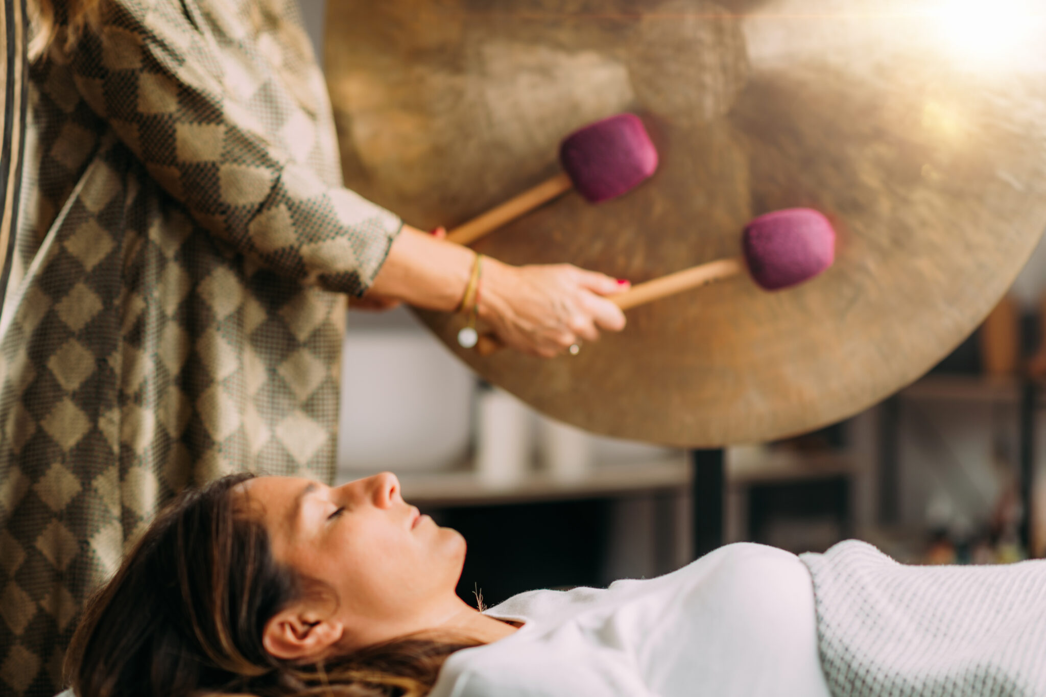 Playing gong in sound bath healing therapy