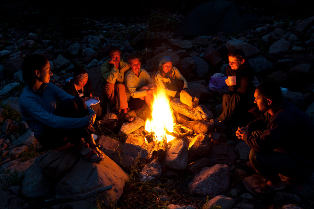 Group of backpackers relaxing near campfire after a hard day, tourist background.